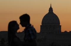The dome of St. Peter's Basilica is seen at sunset as a couple kiss near Villa Borghese in Rome Oct. 11. (CNS photo/Paul Haring)