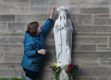 Joanmarie Racette straightens out the wreath she made for the the May Crowning ceremony outside of St. Patrick Catholic Church in Cleveland. St. Patrick has been closed for almost two years.