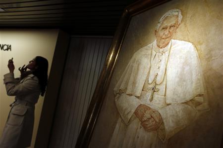 A TV reporter touches up her make-up next to a painting of Pope Benedict XVI after the head of Spain's Catholic Church and President of the Bishops' Conference Cardinal Antonio Maria Rouco Varela addressed the media during a news conference in Madrid February 11, 2013.