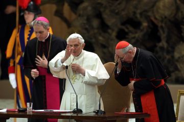 Pope Benedict XVI, flanked by cardinal Agostino Vallini (R) and his personal secretary Georg Ganswein (L), delivers his blessing during a meeting with parish priests of Rome's diocese at the Paul VI Hall on February 14, 2013 in Vatican City, Vatican. The pontiff will hold his last weekly public audience on February 27 at St Peter's Square after announcing his resignation earlier this week. (Franco Origlia/AFP/Getty Images)