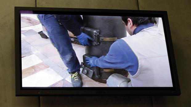Workers carrying the stove in the Sistine Chapel are seen on a screen at the media centre in the Vatican yesterday. The stove will send up white smoke signals when the new Pope is elected.