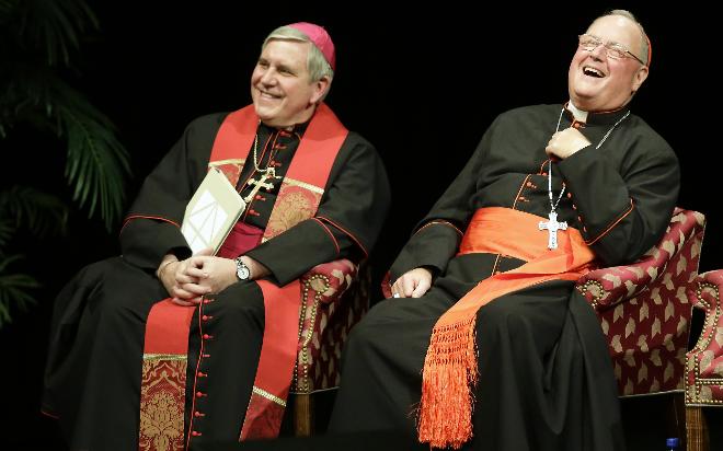 New York Cardinal Timothy Dolan (right) laughs during his introduction with Milwaukee Archbishop Jerome Listecki before addressing before a full crowd Thursday at the Milwaukee Theatre in Milwaukee.