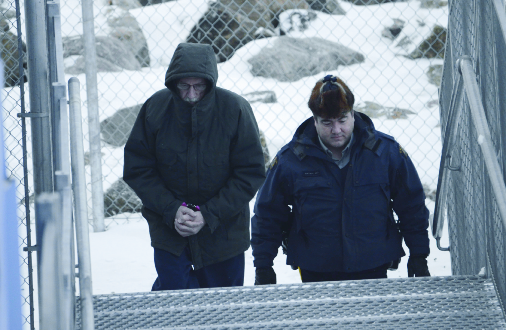 Eric Dejaeger, in pink handcuffs, ascends the steps of the Nunavut Court of Justice in Iqaluit Nov. 20 for day three of his trial. The disgraced Catholic priest faces 69 charges, most of which are sexual offences with minors. (PHOTO BY DAVID MURPHY)