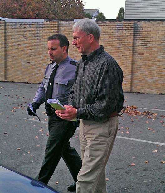 Trooper Ryan Burns escorts Pastor Ray Scott Teets from the office of Masontown District Judge Randy Abraham following Teets’ arraignment Thursday. Teets is accused of having indecent sexual contact with an 11-year-old girl.