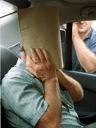 St Anns Special School bus driver Brian Perkins covers face with cardboard after being extradited back to South Australia. Picture: Michael Milnes