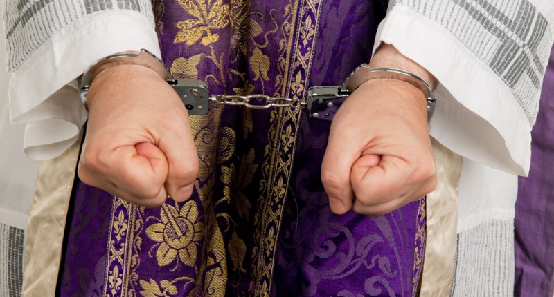 Handcuffs on priest (Shutterstock)
