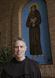 Father Perry in front of a mosaic of St. Francis at his order's headquarters in Rome. (CNS file/Paul Haring)