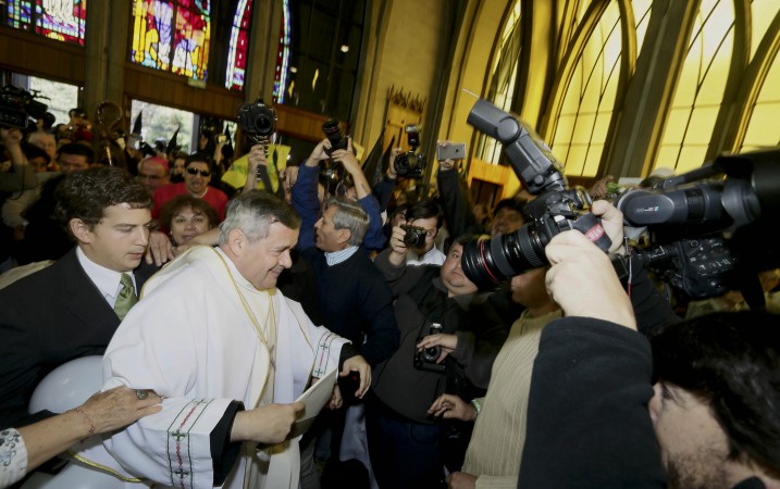 Protestors, background left, shouted as Bishop Juan Barros, center left, entered the cathedral for the ceremony that installed him as bishop of Osorno in southern Chile March 21. (AP Photo/Mario Mendoza Cabrera)