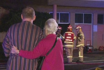 PHOTO: Two people watch as firefighters fight a blaze at St Mary's church in Dandenong, Melbourne on April 1. (ABC News)