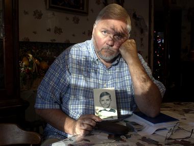 Charlie Bailey, in 2004, with a photo of himself as a 10-year-old: Voice of conscience for victims of abuse.