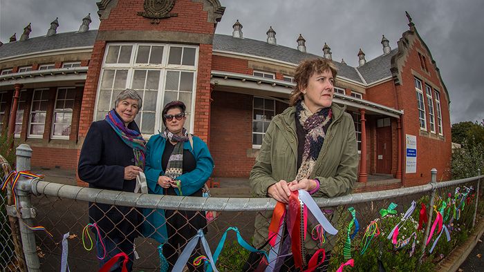 (From right) Maureen Hatcher, Callan Slater and Karen Auchettl have tied colourful ribbons to the fence of the former St Alipius Boy's School to let child sex abuse survivors the community is behind them. (ABC :Margaret Burin)