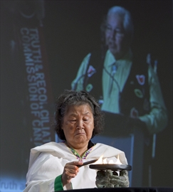 Inuit elder Sally Webster lights a qulliq, a soapstone lamp, as Truth and Reconciliation chair Justice Murray Sinclair speaks during the grand entry ceremony in Ottawa on Monday.