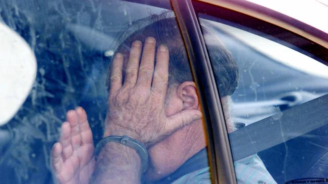 Brian Perkins hides his face as he arrives at a Bundaberg court in 2002.