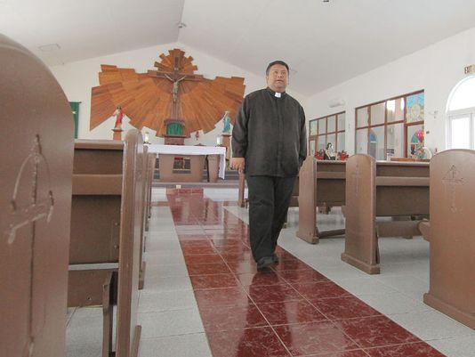 Father Mike Crisostomo, pastor of the Immaculate Heart of Mary Church in Toto, walks the center aisle of the church in July 2014.