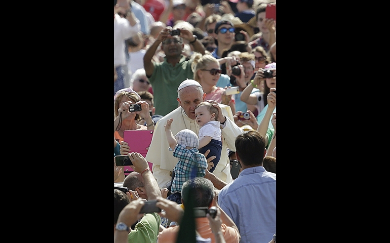 Pope Francis kisses a baby as he arrives to lead his general audience Wednesday in St. Peter's Square at the Vatican. (CNS/Reuters/Max Rossi)