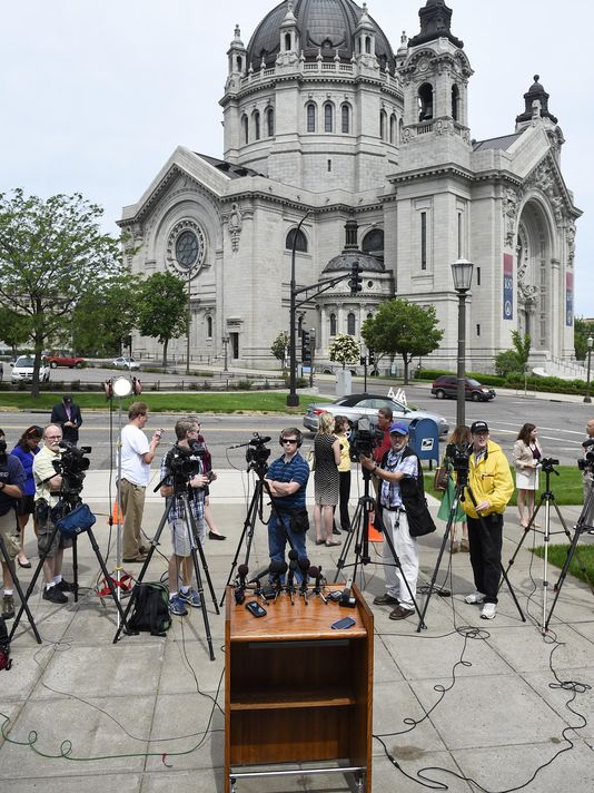 Members of the media wait across the street from the Cathedral of St. Paul for the announcement of the resignations of Archbishop John Nienstedt and Auxiliary Bishop Lee Anthony Piche during a news conference at the Archdiocese of Saint Paul-Minneapolis Chancery on Monday in St. Paul. In the last two years, Nienstedt was besieged by a clergy sex-abuse scandal that included numerous lawsuits from victims and led to bankruptcy. Then earlier this month, the archdiocese was criminally charged with failing to protect children.