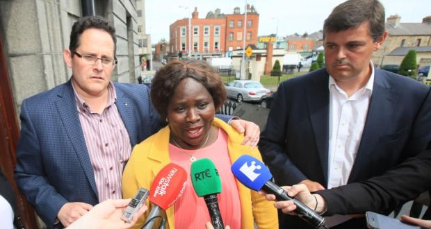 Dolores Atwood, with her husband Chris (left) and RTE’s Kevin Bakhurst (right), speaking to the media on leaving the Four Courts on Thursday, July 2nd, 2015, after the announcement of a settlement in a High Court action for damages taken by former Archbishop of Benin, Richard Burke. Photograph: Collins Courts