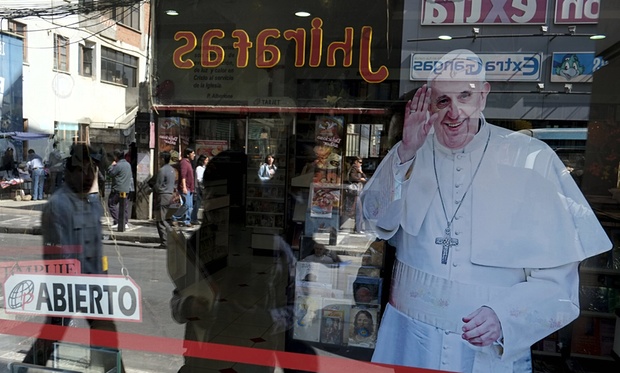 Pedestrians are reflected in a shop window which shows an image of Pope Francis in La Paz, Bolivia. Photograph: David Mercado/Reuters