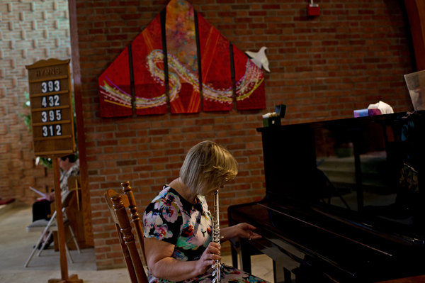 Pamela Nichols, a flutist, was the lone musical accompanist for worshipers at a Sunday service at St. Frances X. Cabrini church. Credit Sean Proctor for The New York Times