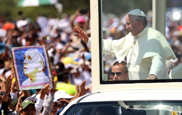 Pope Francis waves from the popemobile as he arrives to celebrate Mass at Samanes Park in Guayaquil, Ecuador, on Monday. (Fernando Vergara / AP)