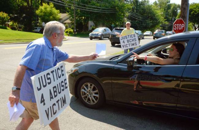 Kevin Waldrip and Robert Hoatson, background, distributing leaflets outside Bergen Catholic High School in Oradell on Thursday.