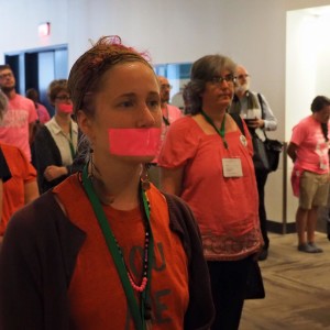 Rachel Halder stands with pink duct tape over her mouth in silent protest with other Pink Menno’s on Thursday afternoon, after the Membership Guidelines resolution was passed.