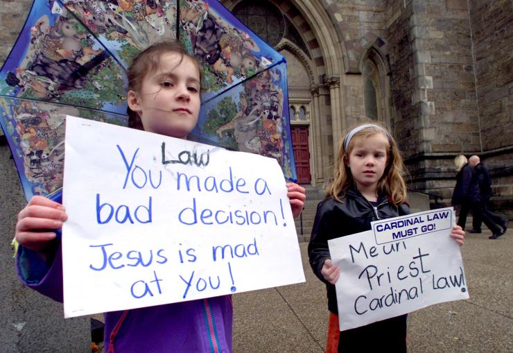 IN PHOTO: Six-year-old twins Allison (L) and Carolyn Monhagan of Hopkinton, Massachusetts protest against Boston's Roman Catholic Cardinal Bernard Law outside Boston's Cathedral of the Holy Cross April 28, 2002 as the Cardinal says a mass of healing inside. Law appears to be holding firm in his resolve not to resign despite continued calls for his resignation over his handling of pedophile priests during the ongoing clergy child sex abuse scandal in the church. REUTERS/Jim Bourg