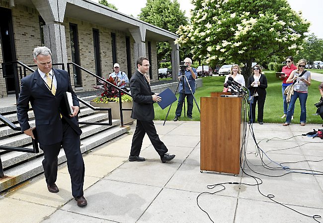 Auxiliary Bishop Andrew Cozzens, center, walks to the podium to announce the resignations of Archbishop John Nienstedt and Auxiliary Bishop Lee Anthony Piche as Tom Halden, left, director of communications for the Archdiocese of St. Paul and Minneapolis, accompanies him during a news conference at the Archdiocese Chancery in St. Paul on June 15, 2015. (AP Photo/Craig Lassig)