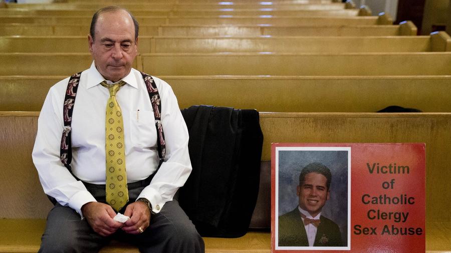 Arthur Baselice, the father of Arthur Baselice III, pictured in poster, sits on a pew after a news conference in Philadelphia last week. Baselice said his son was abused by a priest and a religious brother, became addicted to drugs and killed himself. Baselice said the Vatican needs to find ways to hold church leaders accountable for sheltering predators. (Matt Rourke / Associated Press)