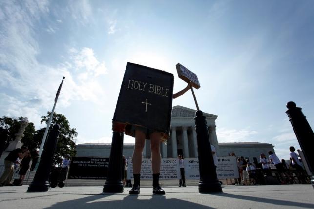 A protester dressed as a copy of the Bible joins groups demonstrating outside the U.S. Supreme Court in Washington June 30, 2014.