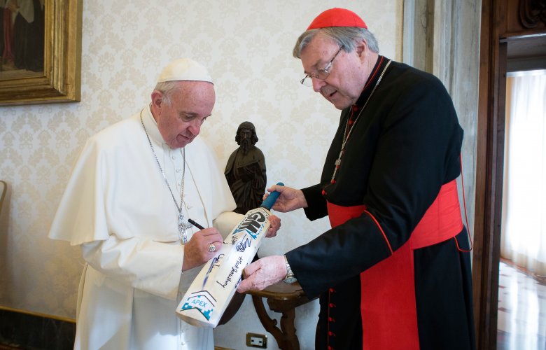 Pope Francis signs a cricket bat presented to him by Cardinal George Pell, at the Vatican last month.