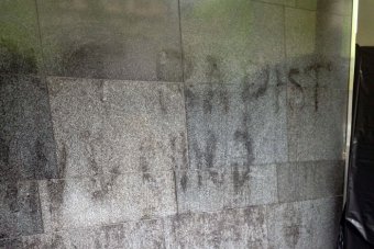 PHOTO: Workers at the court tried to remove the graffiti and have erected black plastic to cover what remained. (ABC News: Danny Morgan)