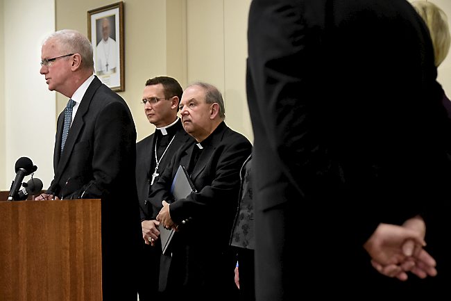 The Rev. Andrew Cozzens, center left, and apostolic administrator Bernard Hebda listen as Judge Tim O Malley discusses the archdiocese's agreement with Ramsey County on Friday, Dec. 18, 2015. (Pioneer Press: Jean Pieri)
