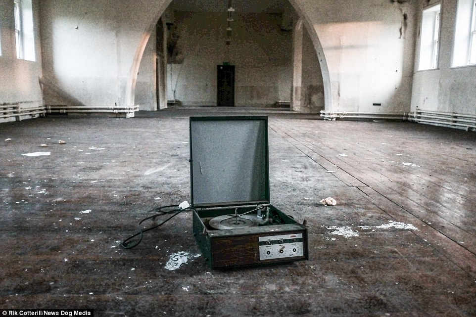A broken, dust-covered record player, once used by the hundreds of pupils that flooded these great halls, sits covered in dust in the middle of the huge space, which is now littered with rubbish and debris