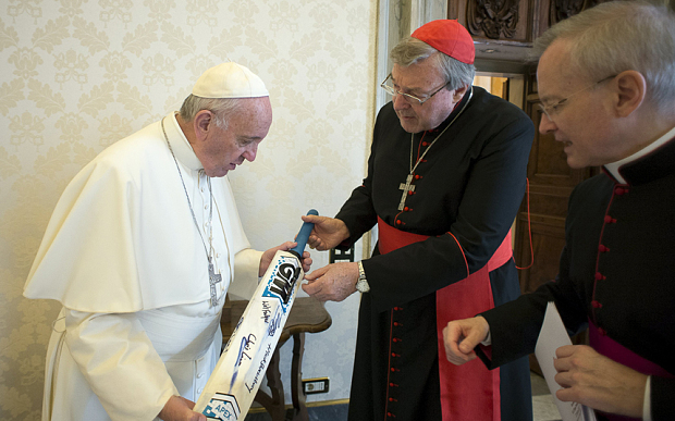 Pope Francis signs a cricket bat, received from Cardinal George Pell, at the Vatican in October last year