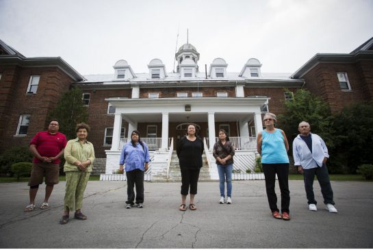 Former Mohawk Institute Indian Residential School students pose in front of their old school in Brantford last June.