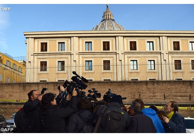 A huddle of journalists surround one of the accused arriving at the Vatican 7 December 2015. - AFP
