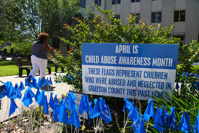 Blue flags at the Grayson Couty Courthouse remind visitors that April is Child Abuse Awareness Month.