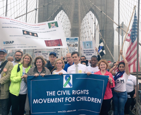 State Senator Brad Hoylman, center, holding banner, and other advocates marched across the Brooklyn Bridge earlier this month in support of a bill to lift the statute of limitations on child sex-abuse lawsuits.