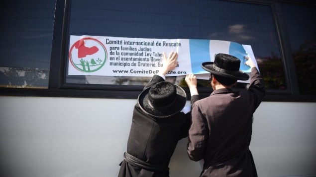 Members of an Orthodox Jewish community put a label from the "International Rescue Committee for Jewish Families of the Lev Tahor Settlement" on the window of a bus in Guatemala city on September 25, 2016. (AFP PHOTO / JOHAN ORDONEZ)