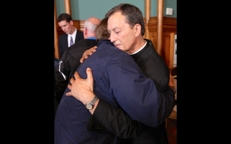 Fr. Charles Lachowitzer, moderator of the curia and vicar general in the St. Paul-Minneapolis archdiocese, hugs an abuse survivor after a news conference to announce a settlement in St. Paul, Minn., on Oct. 13, 2014. (CNS/The Catholic Spirit/Dave Hrbacek)
