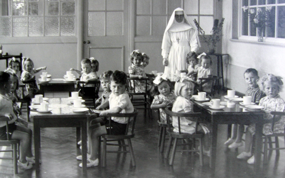 A nun and young children pose for a photo at a Mother and Baby Home.