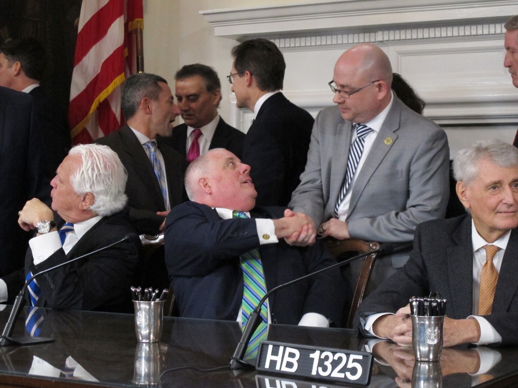 Hogan, sitting, shakes hands with Del. David Fraser-Hidalgo (D-Montgomery) after signing a bill to ban fracking. (Brian Witte/Associated Press)
