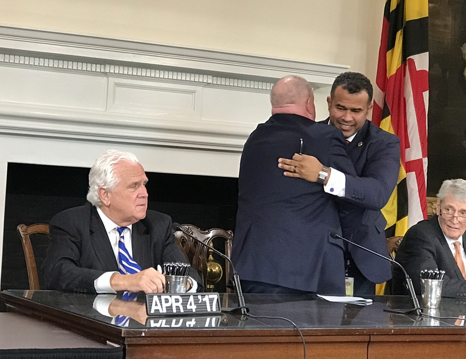 Senate President Thomas V. Mike Miller Jr. (D-Calvert), left, looks on as Gov. Larry Hogan, middle, is embraced by Del. C.T. Wilson (D-Charles). (Ovetta Wiggins/The Washington Post)