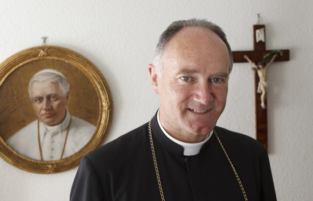 Bishop Bernard Fellay, superior of the Society of St. Pius X, is pictured near an image of St. Pius X at the society's headquarters in Menzingen, Switzerland, in this 2012 file photo. (Credit: CNS/Paul Haring.)