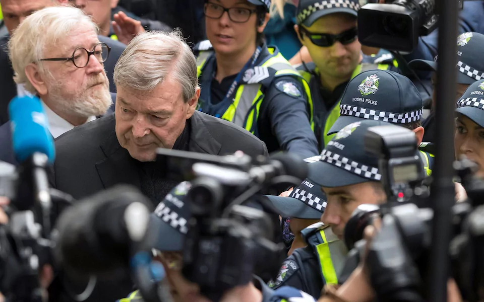 Vatican Treasurer Cardinal George Pell is surrounded by Australian police and members of the media as he leaves the Melbourne Magistrates Court in Australia CREDIT: REUTERS
