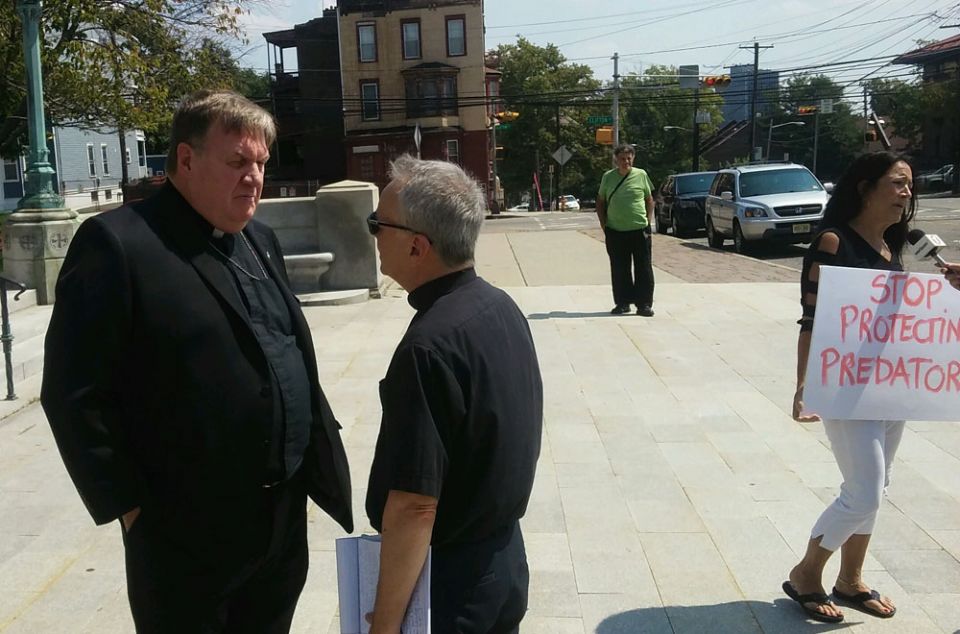 Cardinal Joseph Tobin listens to Fr. Desmond Rossi Aug. 29 in front of Sacred Heart Basilica in Newark. (NCR/Peter Feuerherd)