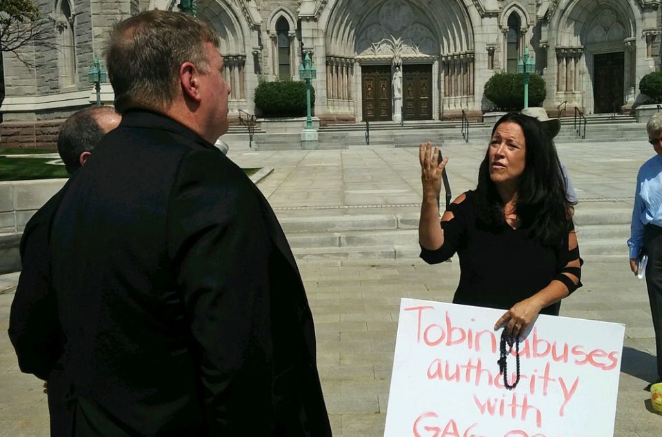 Cardinal Joseph Tobin listens to an attendee of the Aug. 29 prayer demonstration, whose sign reads "Tobin abuses authority with gag order." (NCR/Peter Feuerherd)