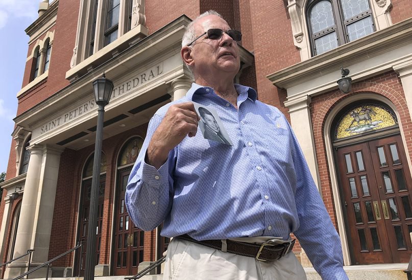 Tim Lennon, president of the Survivors Network of those Abused by Priests, holds a photo of himself as a young boy, in front of the Cathedral of St. Peter in Scranton, Pa., on Aug. 20, 2018. (AP Photo/Michael Rubinkam)