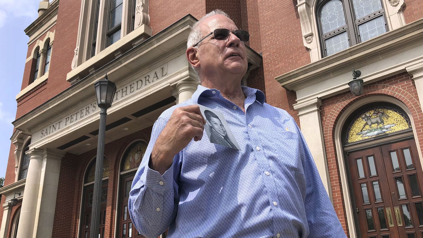 Tim Lennon, president of the Survivors Network of those Abused by Priests, holds a photo of himself as a young boy on Aug. 20 in front of the Cathedral of Saint Peter in Scranton, Pa. (Michael Rubinkam / Associated Press)